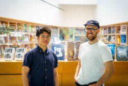 Milton Lim and Patrick Blenkarn stand side-by-side in a library, smiling at the camera.