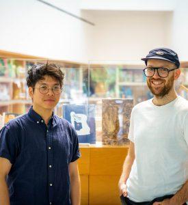 Milton Lim and Patrick Blenkarn stand side-by-side in a library, smiling at the camera.